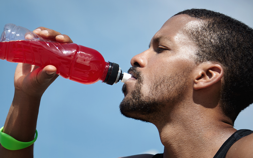 An athlete drinking an electrolyte sports drink, illustrating the match-day hydration cycle and fueling strategy for the Silver Studs FC academy.